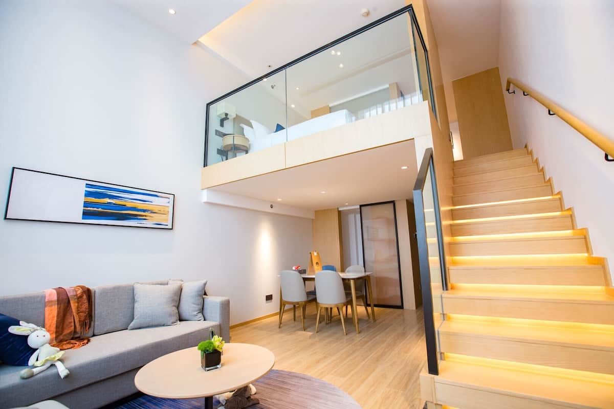 Un appartement moderne avec une chambre en mezzanine, un coin repas et un escalier.
