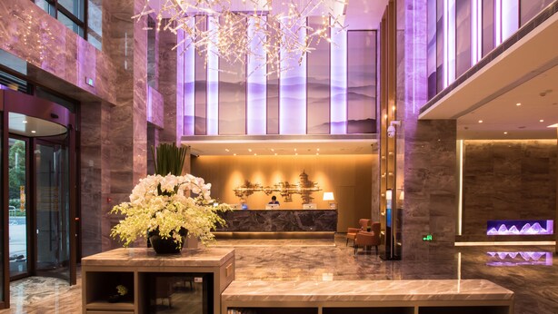 A modern lobby with a reception desk, seating area, and a decorative ceiling light fixture.