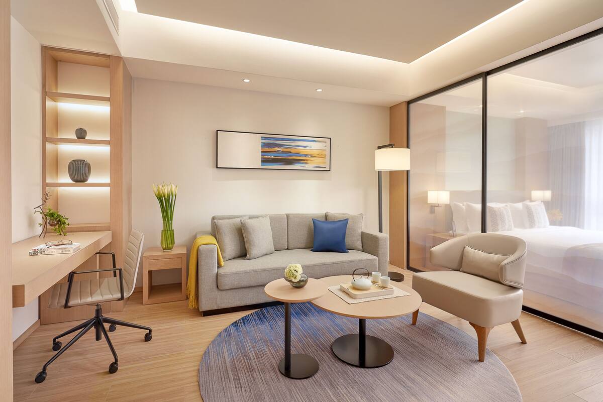 Une chambre d’hôtel moderne équipée d’un canapé, d’un bureau, d’une chaise, d’un lit et d’une grande fenêtre.