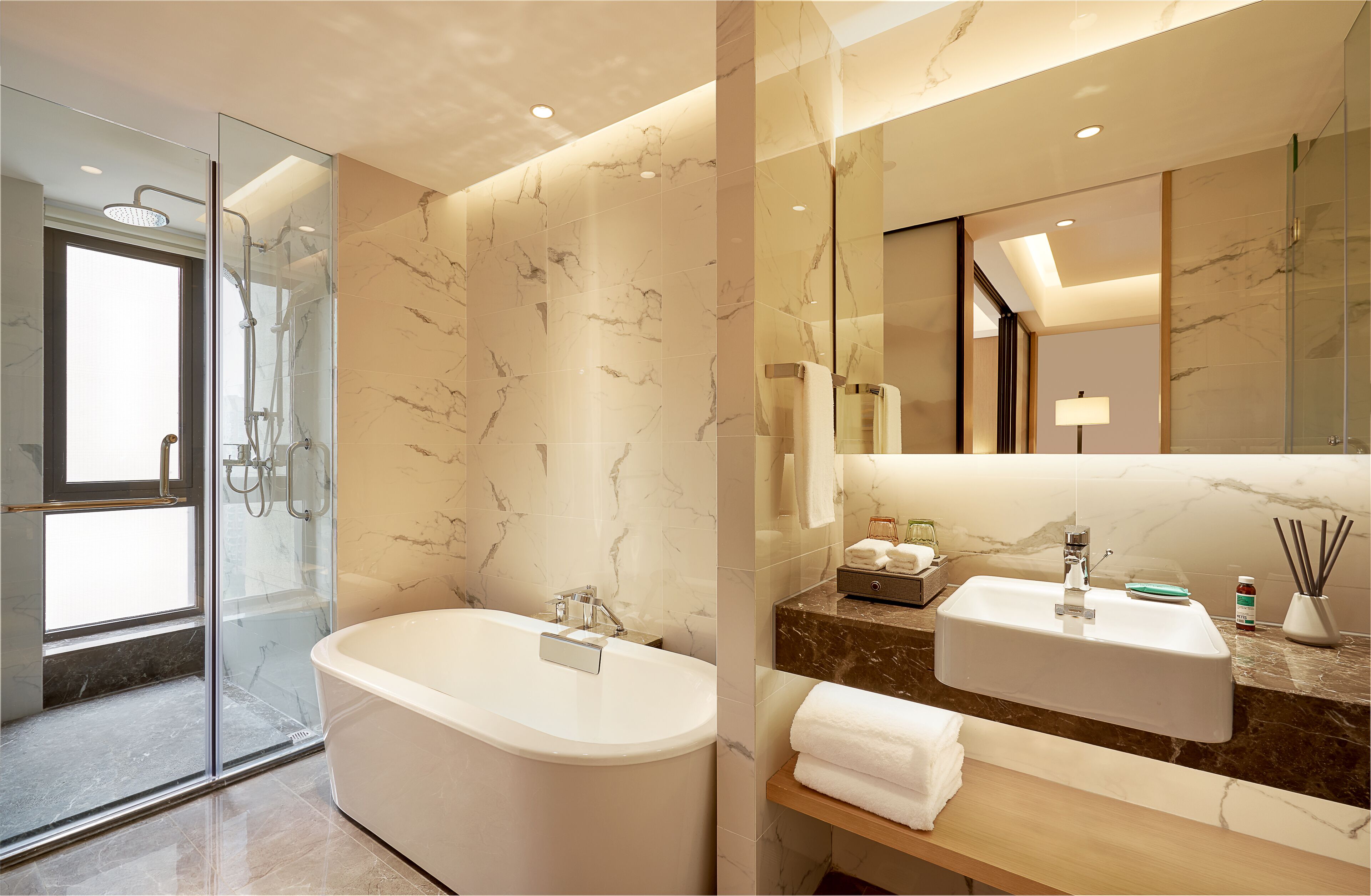 Un baño moderno con ducha envuelta en vidrio, una bañera independiente y un tocador con lavamanos y espejo.