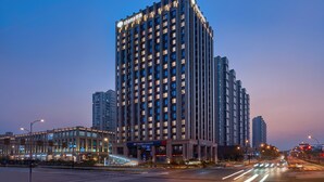 A high-rise building with illuminated windows and a sign for Shimao Hotel.