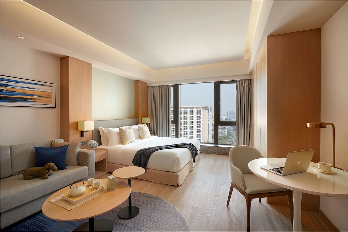 Une chambre d’hôtel moderne équipée d’un lit, d’un canapé, d’une table basse et d’un bureau avec un ordinateur portable.