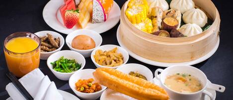 Una variedad de platos que incluyen dumplings, fruta y sopa, dispuesta sobre una mesa.