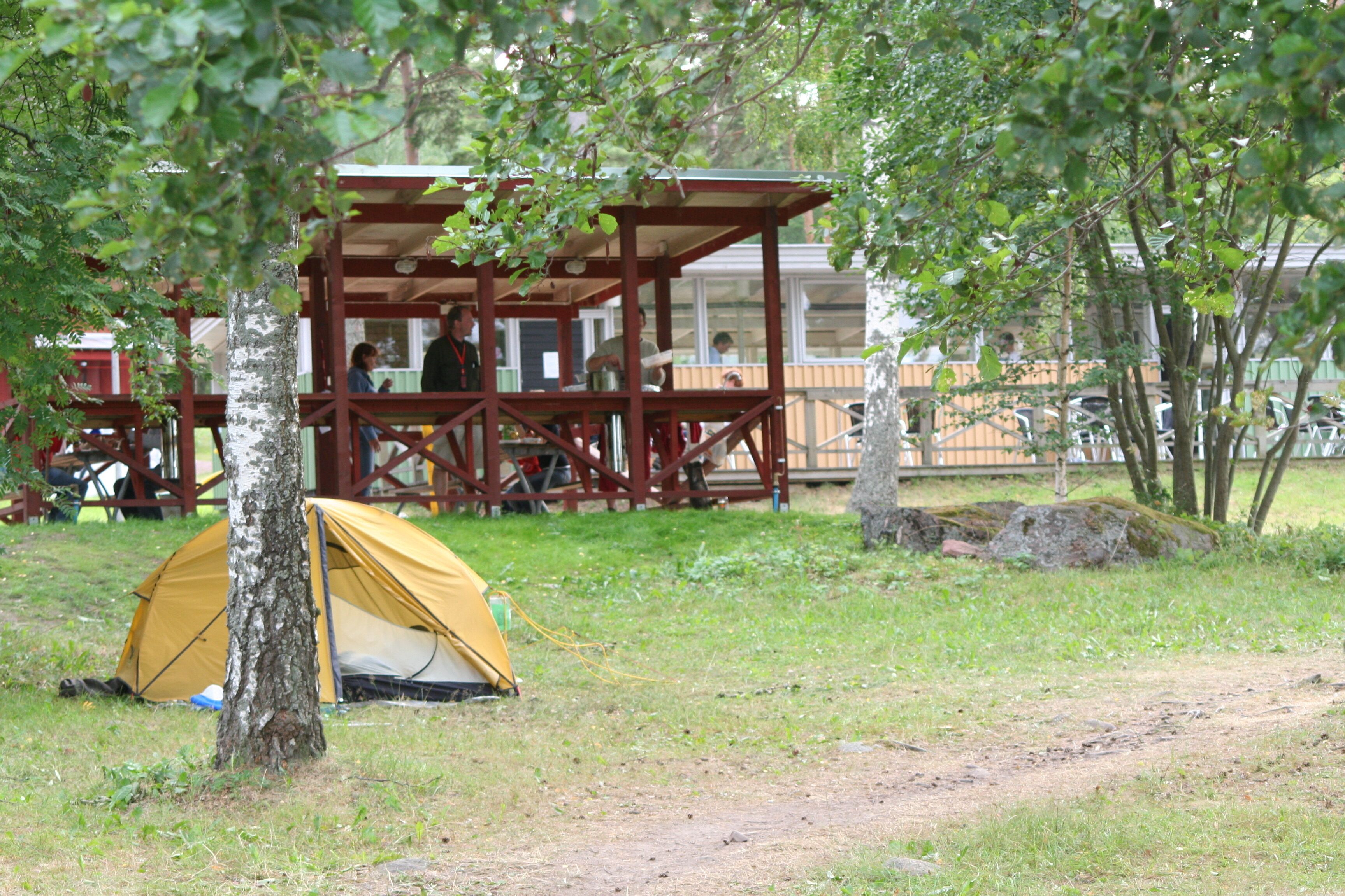 A camping area with a yellow tent, a wooden shelter, and a picnic table.