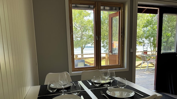 A dining area with a table set for four, including plates, glasses, and cutlery. - Gröna Uddens Camping (Mariehamn)