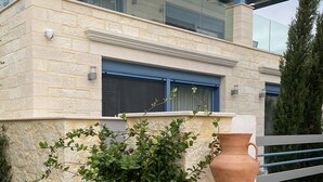 En modern byggnad med en fasad av sten, en balkong av glas och en stor terrakottakruka.