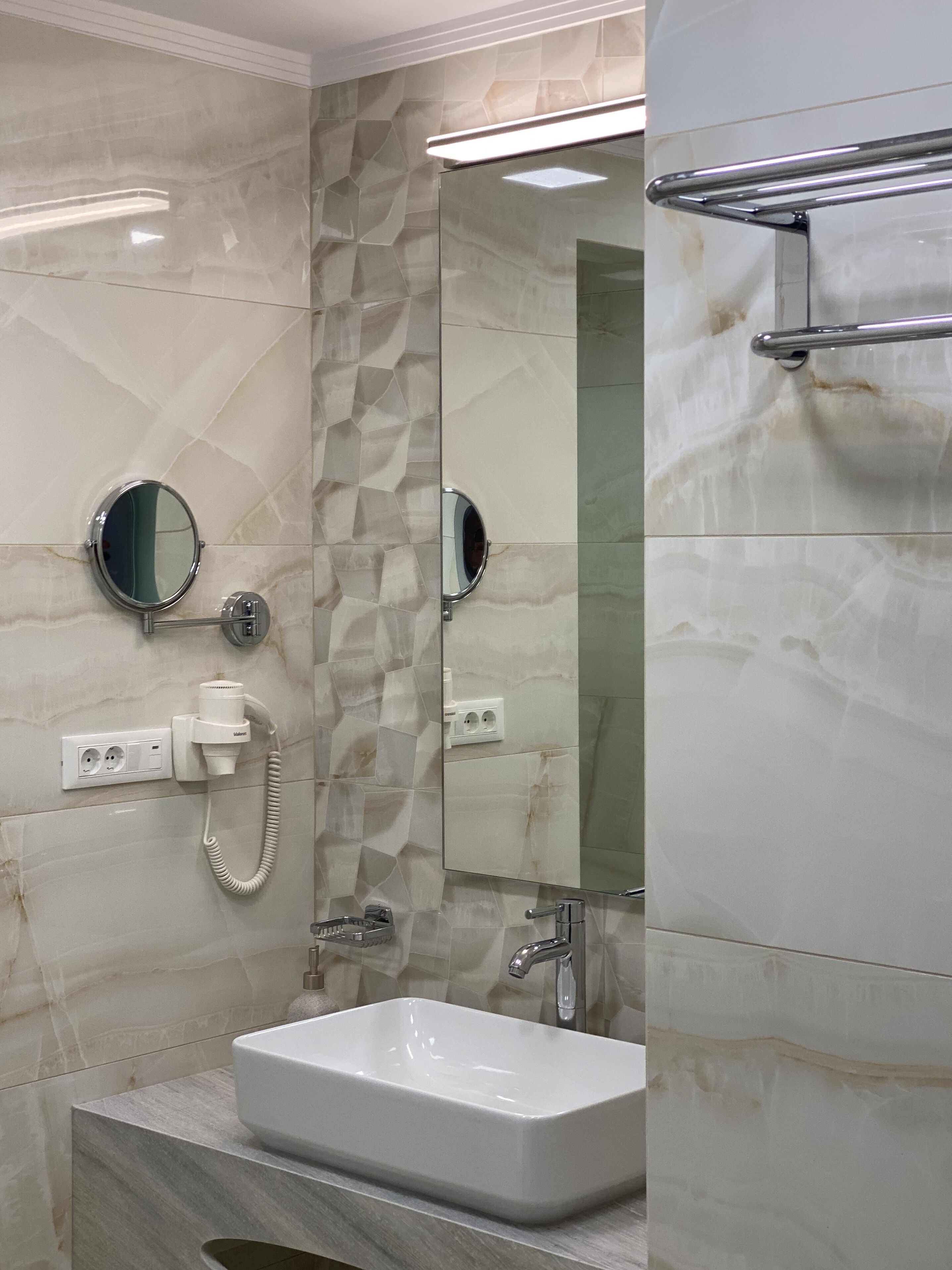 A bathroom with a white sink, a mirror, and a towel rack.