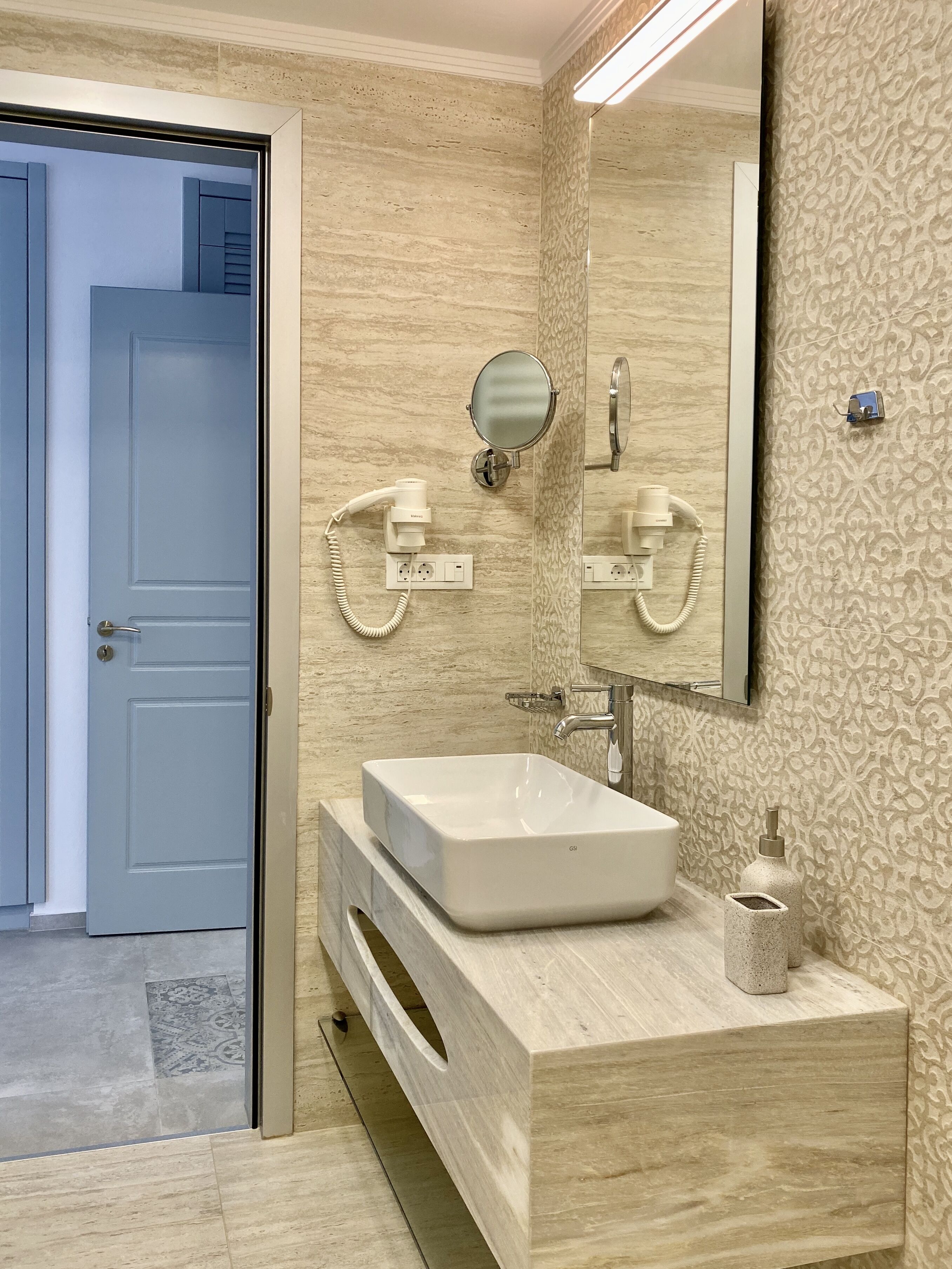 Une salle de bain moderne avec un grand miroir, un lavabo et un sèche-cheveux.