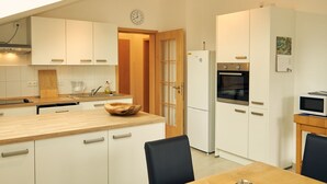 Una cocina moderna con armarios blancos, encimera de madera, horno empotrado y microondas.