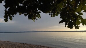 Un lago tranquilo con una orilla lejana y montañas.