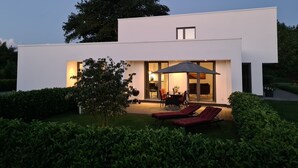 A modern house with a patio area featuring outdoor furniture and a large umbrella. - Eilers, Katja Lilly, Ferienwohnung Lilly - Ferienwohnung Lilly (Varel)