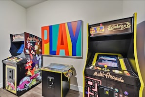 Tre macchinette arcade con disegni colorati e la scritta 'PLAY' ben visibile.