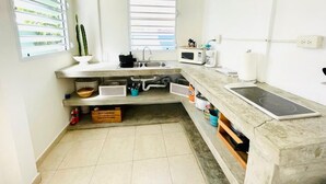 Une cuisine de taille réduite équipée d’un four à micro-ondes, d’un évier et d’un luminaire suspendu.