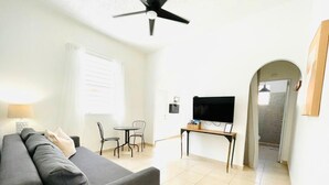 Un salon avec un canapé, un téléviseur, une table et un ventilateur de plafond.
