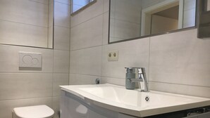 A modern bathroom with a white toilet, a sink with a faucet, and a mirror above the sink. - "elise" Apartments Nr.1 2019 Hochwertig Eingerichtetes Apartment (Mücheln (Geiseltal))