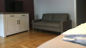 A room with a sofa, a TV on a cabinet, and a bed with a pillow. - "elise" Apartments Nr.1 2019 Hochwertig Eingerichtetes Apartment (Mücheln (Geiseltal))
