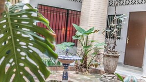 A courtyard with a decorative fountain, potted plants, and a door. - Beautiful apt 2 rooms Cathedral views cn WIFI (Sevilla)