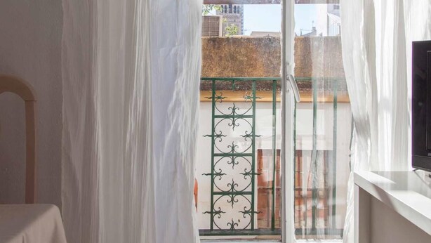 A room with a view of a building with a tower through a window with white curtains. - Beautiful apt 2 rooms Cathedral views cn WIFI (Sevilla)