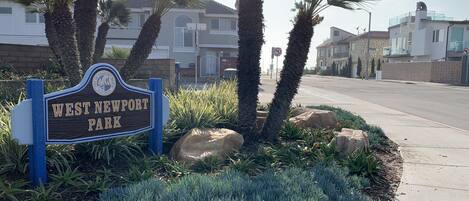 A sign for West Newport Park with a clear sky and residential buildings in the background.