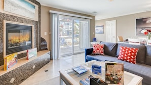 A modern living room with a fireplace, a sofa with patterned cushions, and a dining area with a table set for two. - Amazing Family Friendly Newport Beach Home - 1 Block To Ocean (C2) (Newport Beach)