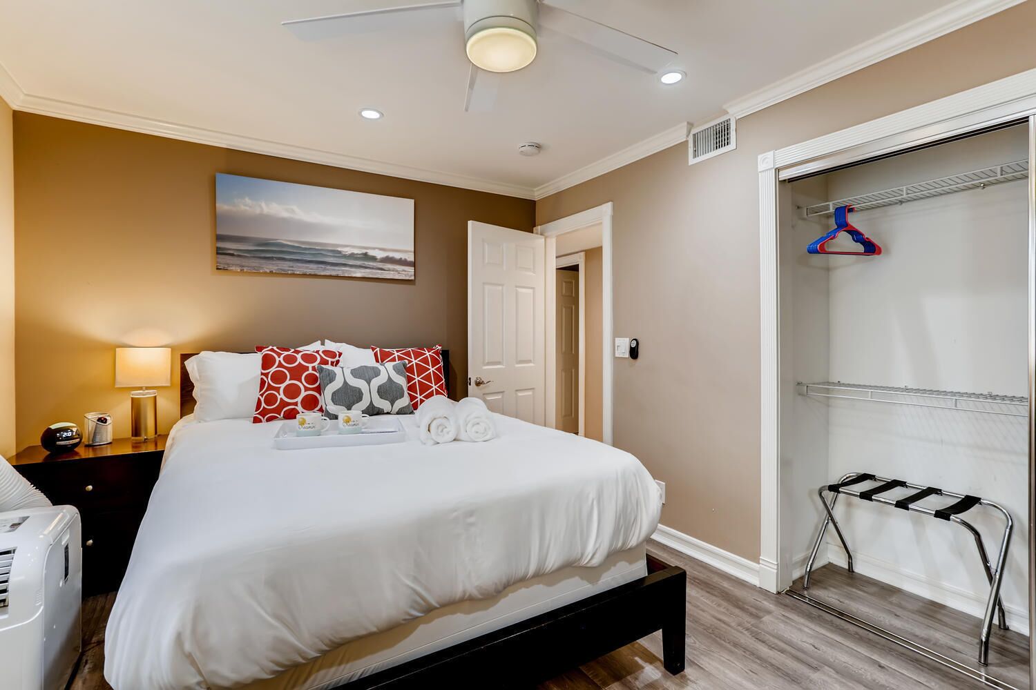 A hotel room with a bed, bedside table, lamp, and a view of a closet with hangers.