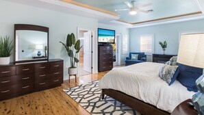 A bedroom with a bed, dresser, and a television. - Beach Bay Serenity: Pine Ave canal front pool home (Anna Maria)