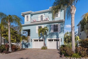 A two-story house with a light blue exterior, a balcony, and a garage.