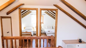 Een kamer met houten balken, een witte kast en twee bedden.