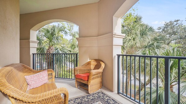 A balcony with wicker furniture and a view of tropical vegetation.