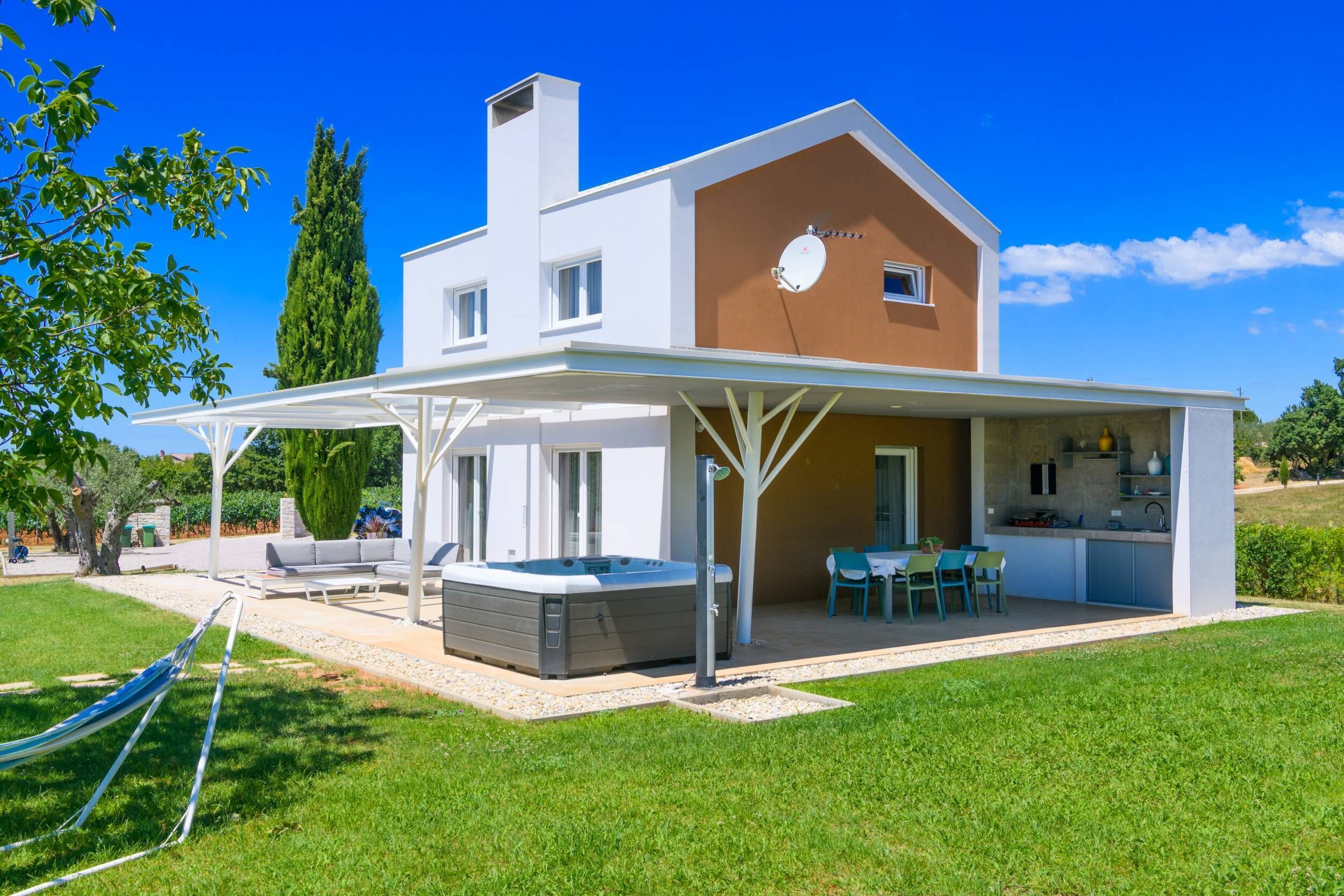 Une maison moderne à deux étages dotée d’un patio couvert, d’un espace salon extérieur et d’un jacuzzi.