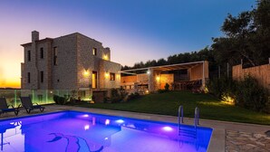 Un bâtiment moderne en pierre, doté d’une piscine, d’un espace extérieur aménagé et d’une pelouse bien entretenue.
