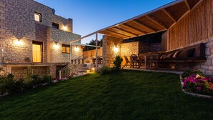 Un bâtiment en pierre doté d’un patio couvert, d’un espace extérieur aménagé pour s’asseoir et d’une pelouse bien entretenue.