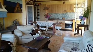 Una sala de estar acogedora con un sofá, una mesita de centro y un comedor con mesa y sillas. Hay una zona de cocina con estufa y fregadero.