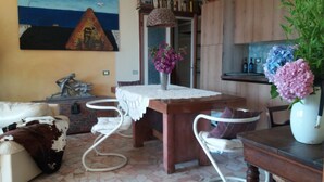 Un salón acogedor con un sofá, una mesa de comedor con sillas, una estantería y un cuadro en la pared.