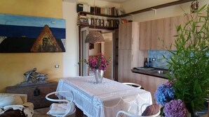 Un comedor con una mesa dispuesta para dos, un florero con flores y vistas a la cocina.
