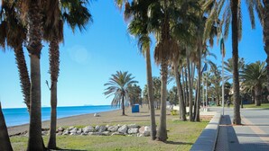 A coastal walkway lined with palm trees and a beach in the background. - First floor Beach side property, San Pedro (Marbella)