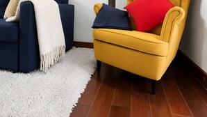 Une pièce avec un canapé bleu, un fauteuil jaune et un tapis à poils longs blanc.