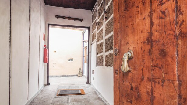 Un couloir avec une porte en bois, un extincteur et un tapis sur le sol.