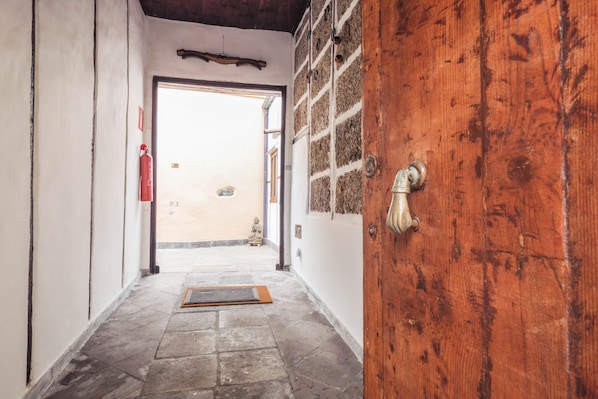 Un pasillo con una puerta de madera, un extintor y un felpudo en el suelo.
