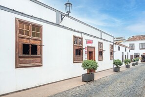 Ein weißes Gebäude mit Holzläden, einem Schild mit der Aufschrift 'HotelStar' und Blumentöpfen an einer gepflasterten Straße.