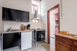 Eine kompakte Küche mit Geschirrspüler, Backofen und einer kleinen Arbeitsfläche mit Kaffeemaschine.