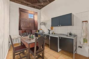 Una cocina compacta con una mesa de madera, sillas, microondas y armarios.