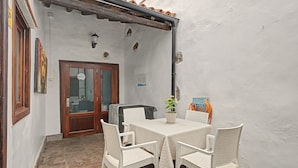 Un patio con una mesa, sillas, una puerta y una pared con un letrero.