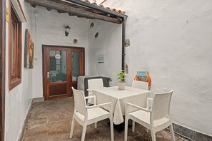 Un patio con una mesa, sillas, una puerta y una pared con un letrero.