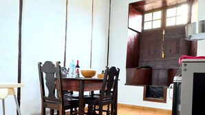 Un comedor con mesa y sillas de madera, suelo de baldosas y ventana con vistas al exterior.