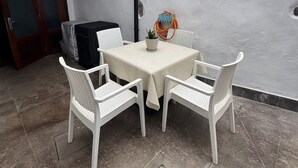 Un patio con una mesa, cuatro sillas, una parrilla y una pared con una puerta que dice 'GARA'.