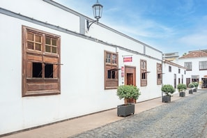 A white building with wooden shutters, a sign for 'HotelStar,' and potted plants along a cobblestone street.