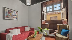 Una sala de estar con un sofá rojo, una mesa de centro de madera y un sillón de mimbre.