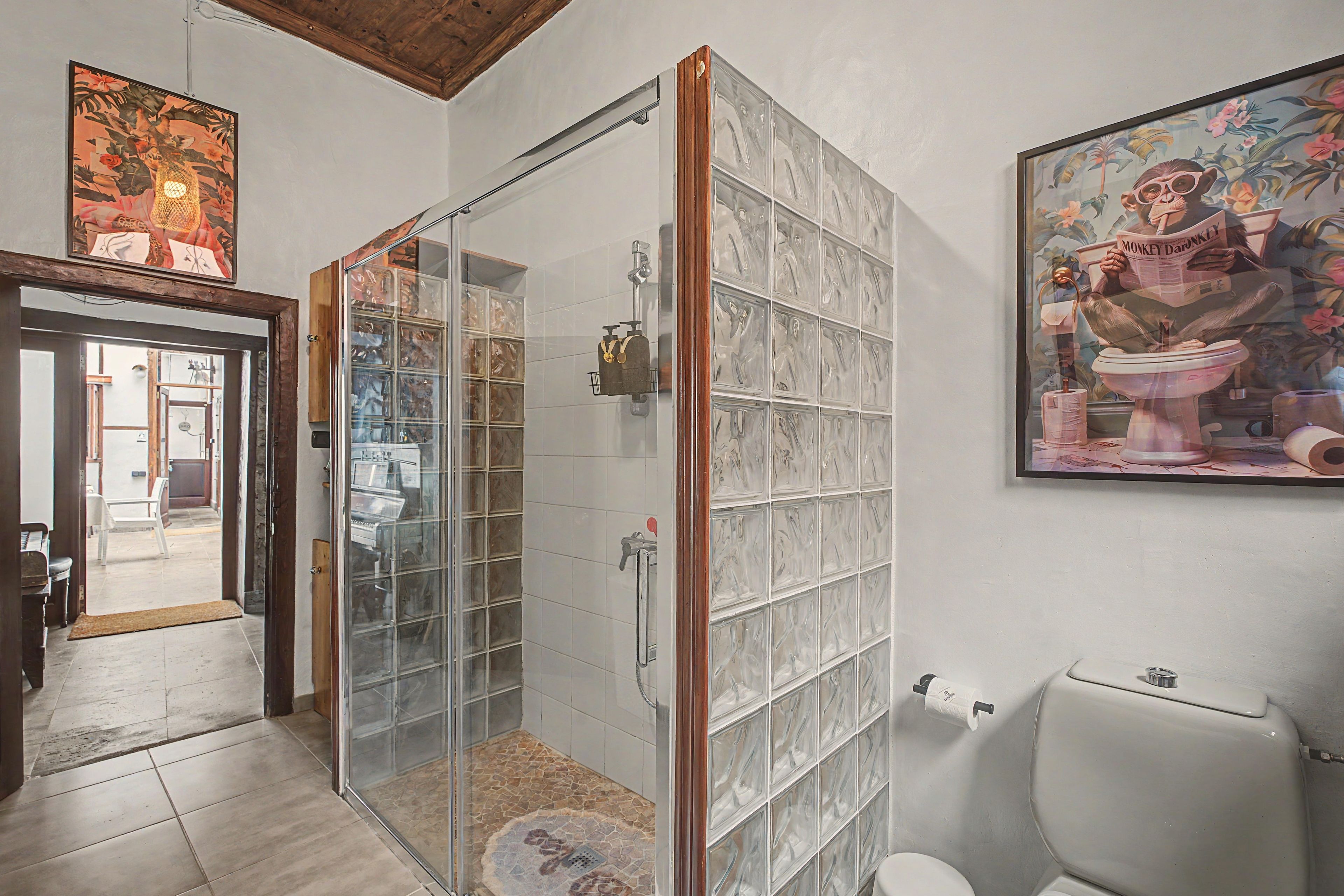 Une salle de bain avec une douche à parois de verre, des toilettes et un lavabo fixé au mur.
