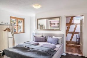 Une chambre à coucher avec un lit, un miroir, une fenêtre et une vue sur une structure en bois à l’extérieur.